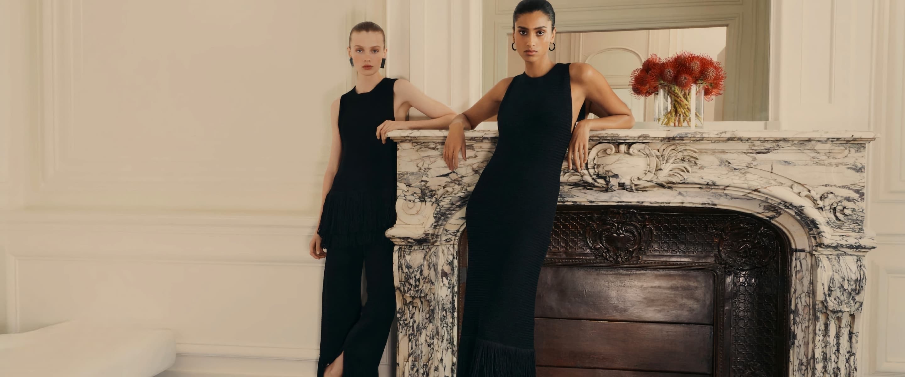 Two models wearing Modimal black dresses in an elegant interior